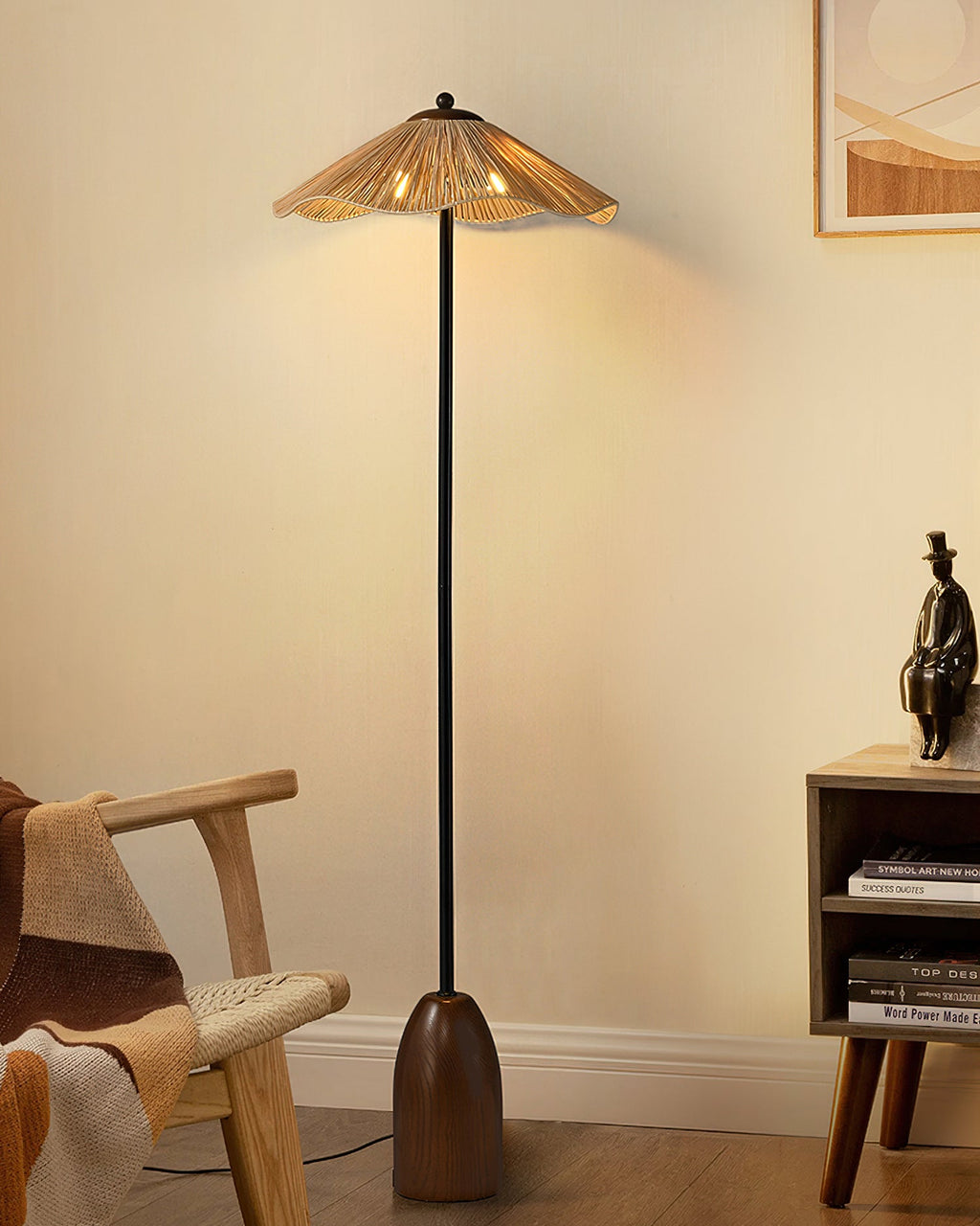 The Clérachic floor lamp's raffia shade glows warm above a rattan armchair and a small wooden shelf, with a figurine nearby.