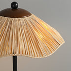 Close view of the wavy raffia shade of this Clérachic lamp, lit from within, with its dark walnut top cap and black finial.