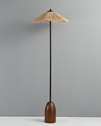 The Clérachic floor lamp with its raffia shade unlit, standing on a pale floor against a grey wall.