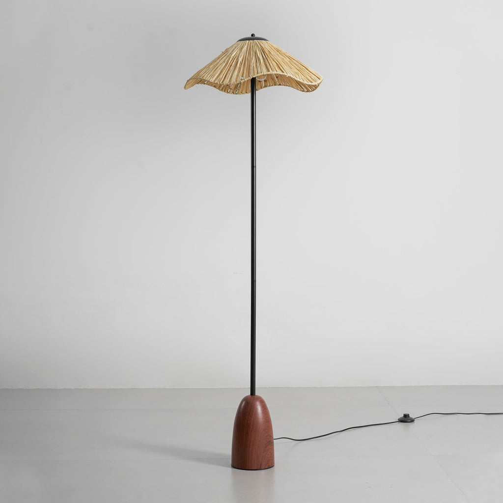 Full view of the Clérachic raffia-shade floor lamp on a grey floor, with its black cord and foot switch trailing off to the right.