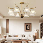Clérachic Flora chandelier lit in a cream living room above a low sofa and round timber tables.