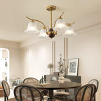 The Clérachic Flora chandelier lit above a round dining table ringed with rattan chairs.