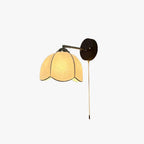 Wall light with a cream scalloped fabric shade, a slim arm and a round dark wood plate with a pull chain, on white, from Clérachic.