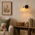 Clérachic scalloped-shade wall light in a child's reading corner, with a teddy bear, a basket and a low wooden shelf.