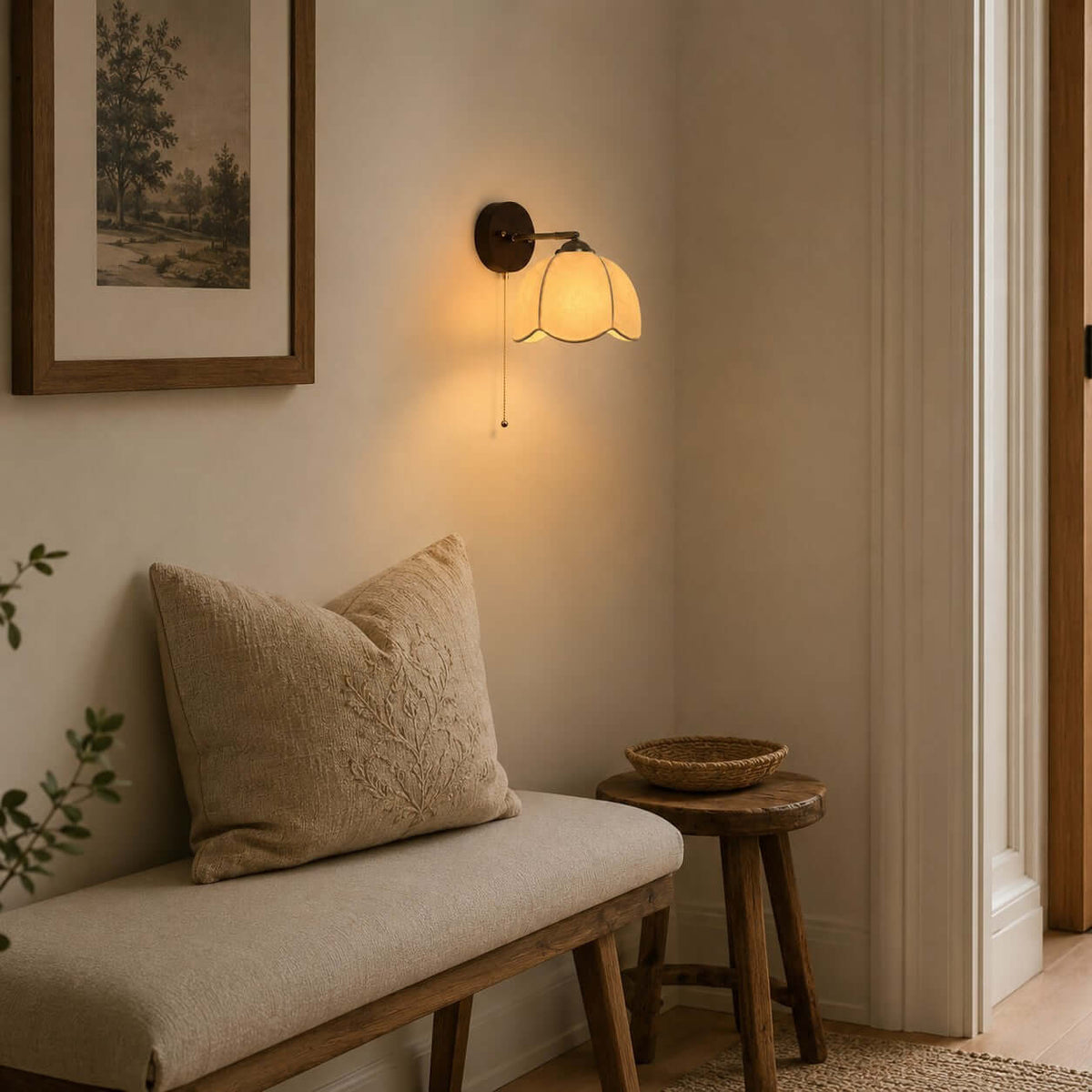 Clérachic wall light in a hallway nook above a cushioned bench and a small wooden stool, beside a framed landscape.