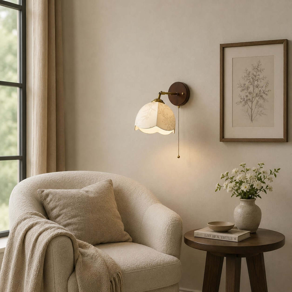 Clérachic wall light with an unlit fabric shade above a boucle armchair and a round table, with a framed botanical print.