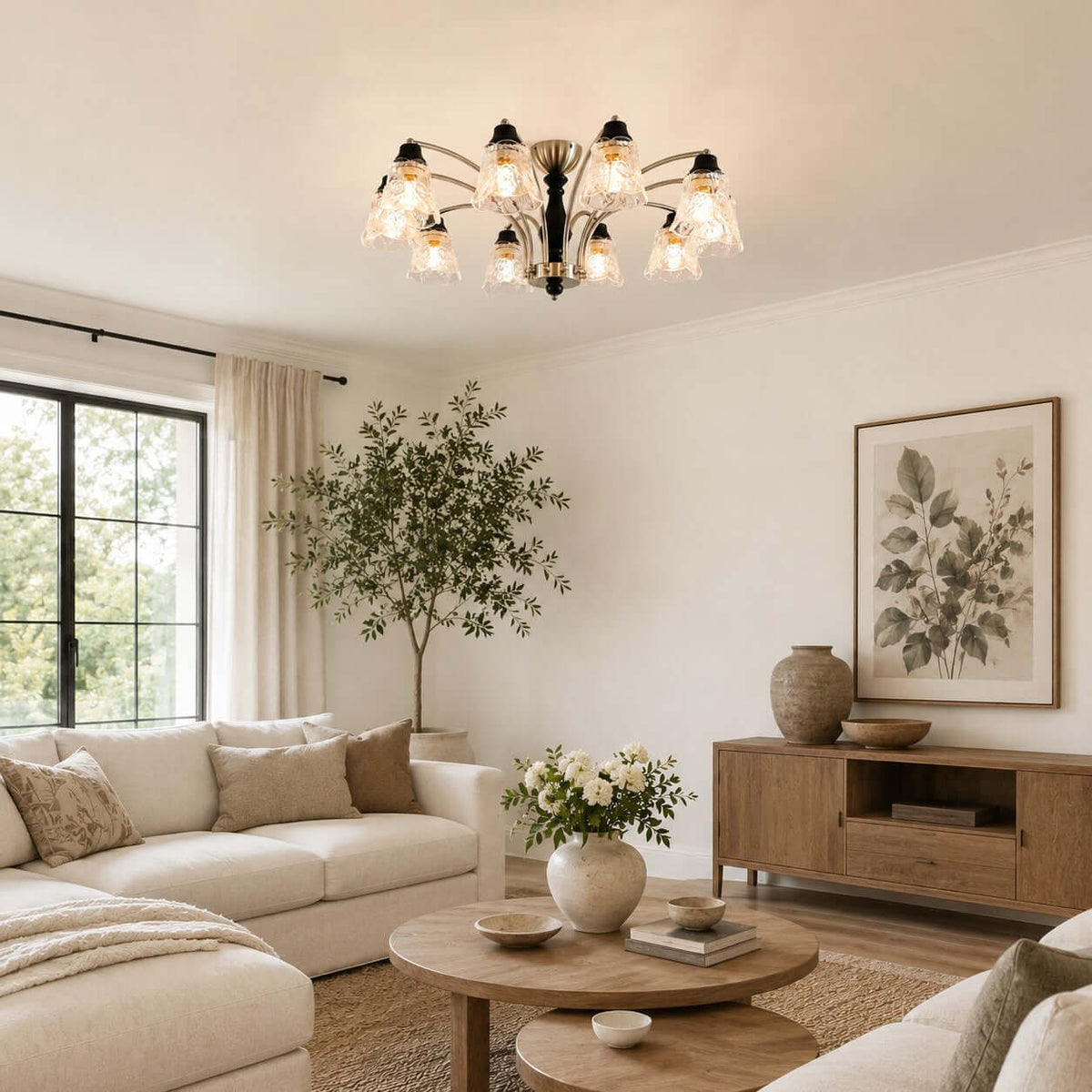 Clérachic multi-arm ceiling light lit above a cream sectional, a round wood coffee table and a potted olive tree.