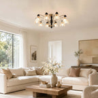 This Clérachic glass-shade chandelier hangs in a sunlit living room with tall black-framed windows and a pale sofa.