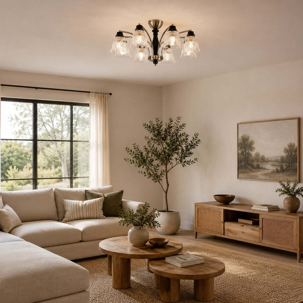 Clérachic chandelier with clear floral shades above stacked round wood tables, a corner sofa and a woven media unit.