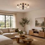 Clérachic chandelier with clear floral shades above stacked round wood tables, a corner sofa and a woven media unit.