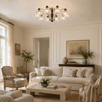 Clérachic multi-light chandelier in a panelled cream living room with a French-style armchair and a landscape painting.