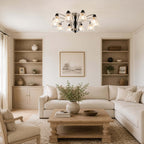 Clérachic chandelier lit above a cream corner sofa and a chunky wood coffee table, between two built-in shelving units.
