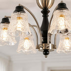 Close view of the floral, rippled clear glass shades, black wooden stem and nickel arms on this Clérachic chandelier.