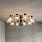 Lit Clérachic ten-light chandelier on a grey concrete-look ceiling, with all its floral glass shades glowing warm.