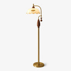 Floor lamp with a scalloped cream glass shade, floral print, curved brass arm and walnut-toned wooden grip, shown on white; a Clérachic design.