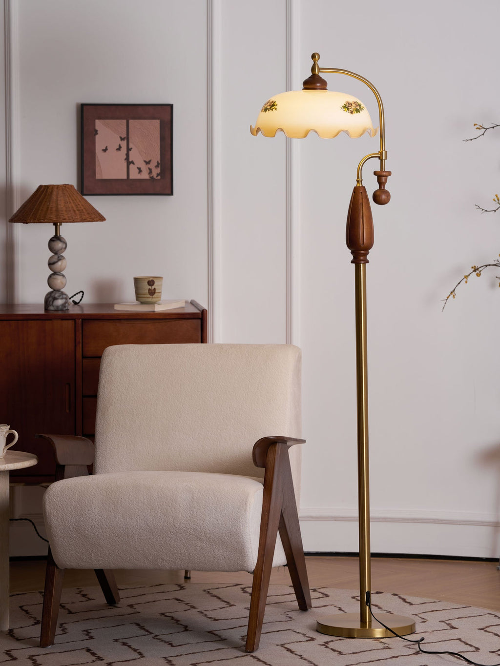 Closer crop of the lit frilled shade and walnut grip, with a framed print and a sideboard in the background; a Clérachic floor lamp.