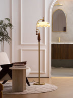 Tall view through an arched doorway, with the floor lamp lit beside a side table and an armchair; a Clérachic design.
