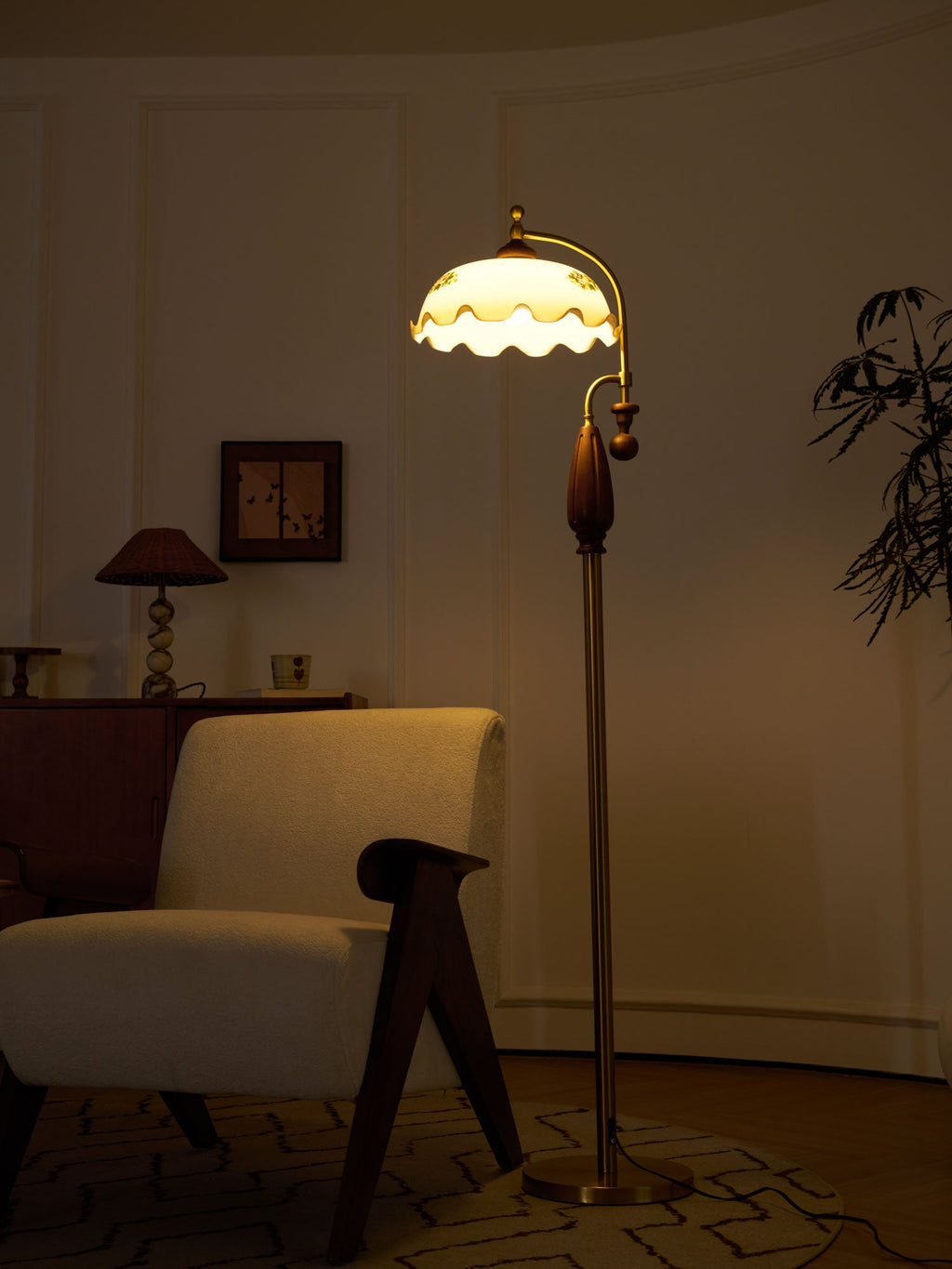 Glowing amber at dusk, the lit frilled shade stands above an armchair and a patterned rug; a Clérachic floor lamp.