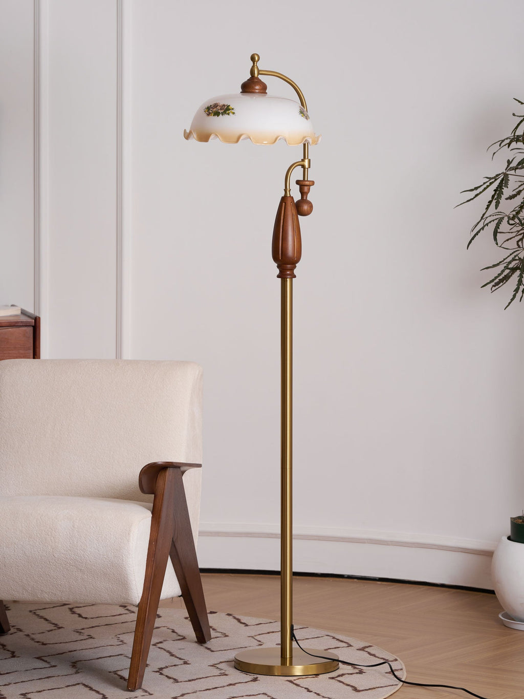 Floor lamp unlit beside a boucle armchair and a pale wall, with a plant at the right edge; a Clérachic design.