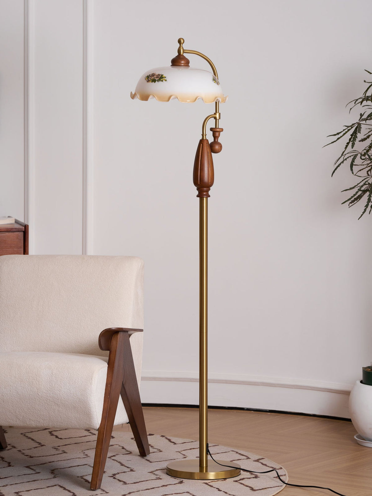 Floor lamp unlit beside a boucle armchair and a pale wall, with a plant at the right edge; a Clérachic design.