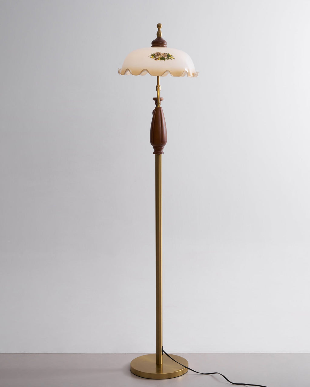 Straight-on studio view of the floral shade at the top of a slim brass stem, against light grey; a Clérachic floor lamp.
