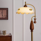 Lit shade with two floral prints, shown above the walnut grip and brass stem, with a framed print and a small cup behind; a Clérachic lamp.
