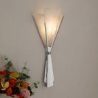 Clérachic Florent sconce lit close on grey, warm light glowing through the stone fan.