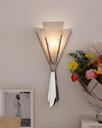 The Clérachic Florent sconce lit beside fresh flowers and a framed fashion print.