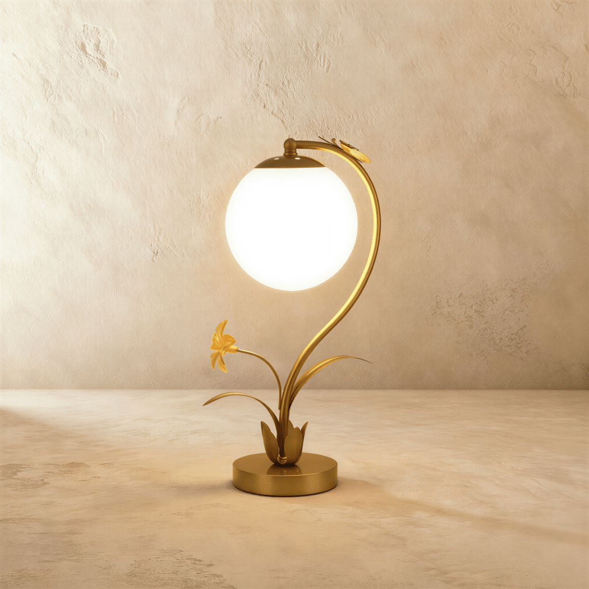 Clérachic gold table lamp with a glowing plain opal white sphere on a curved stem, metal flower and leaves at the base.