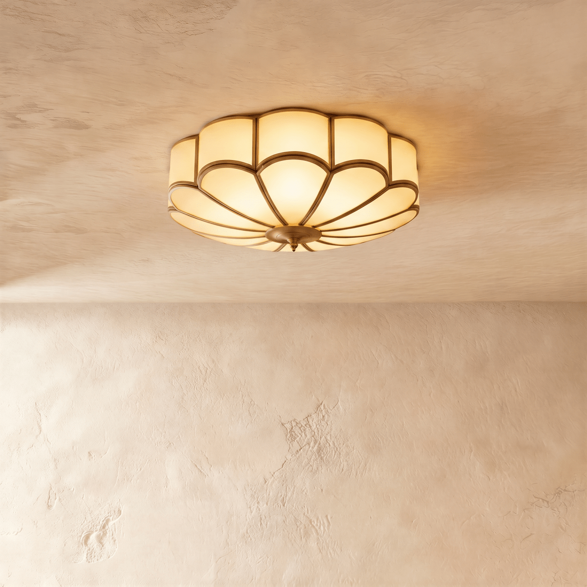 Clérachic scalloped flush ceiling light with frosted glass panels and brass-toned ribs, glowing warm on a limewashed ceiling.