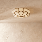 Clérachic scalloped flush ceiling light switched off, frosted glass panes set in slim brass-toned ribs on a plaster ceiling.