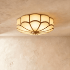 Clérachic wide scalloped flush ceiling light, lit warm, with frosted glass panels and a brass-toned centre boss.