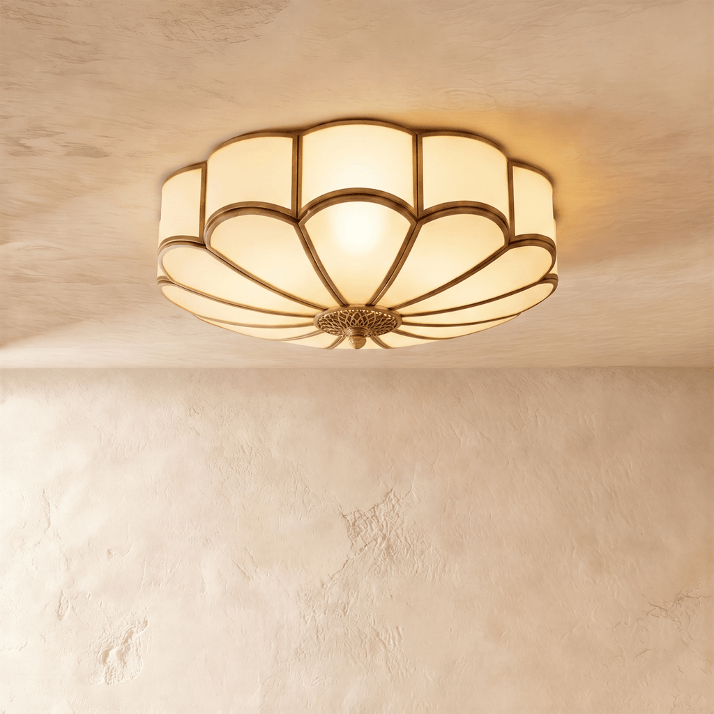 Clérachic largest scalloped flush ceiling light, lit warm, with an ornate brass-toned centre rose on a plaster ceiling.