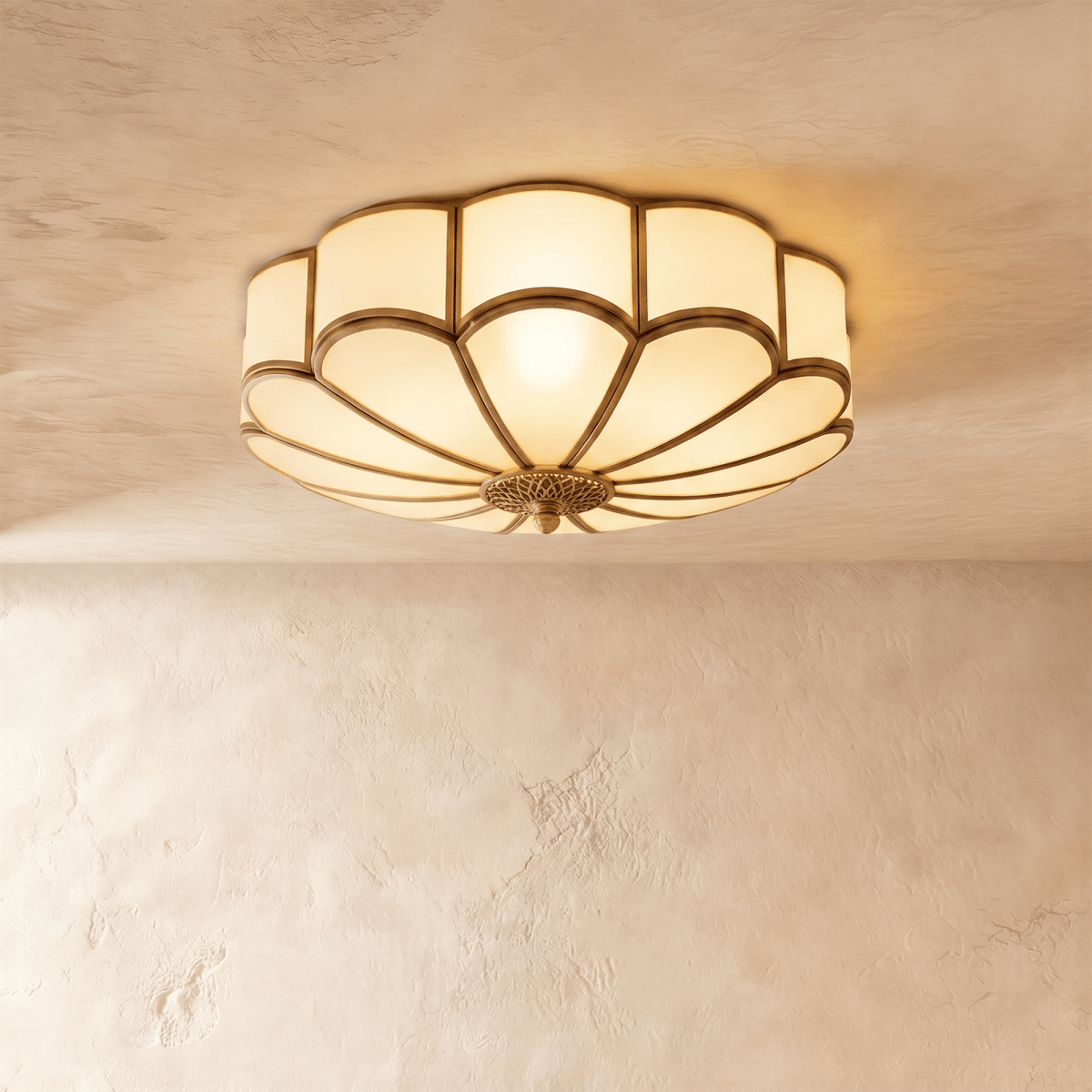 Clérachic largest scalloped flush ceiling light, lit warm, with an ornate brass-toned centre rose on a plaster ceiling.