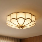 Clérachic scalloped flush ceiling light close up from below, lit warm with frosted glass and brass-toned ribs.