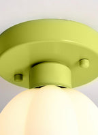 Close view of the green canopy and fixing screws of this Clérachic light, with the top of its white glass shade glowing below.