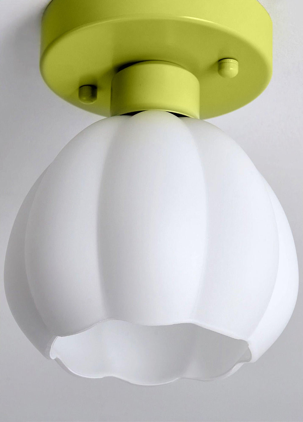 Close view of this Clérachic light shade, a white ribbed glass bell with a scalloped rim, hung from a green canopy against a grey ceiling.
