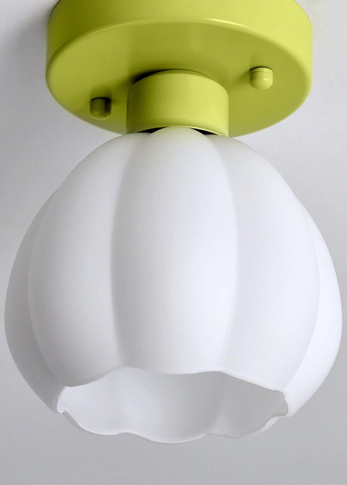 Close view of this Clérachic light shade, a white ribbed glass bell with a scalloped rim, hung from a green canopy against a grey ceiling.