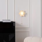 This Clérachic wall light sits high on a panelled wall above a black cabinet with magazines, a cream armchair at the corner.