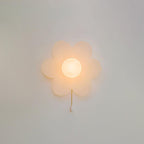 Softly lit white flower wall light on a pale grey wall, this Clérachic sconce showing warm light through its frosted petals.