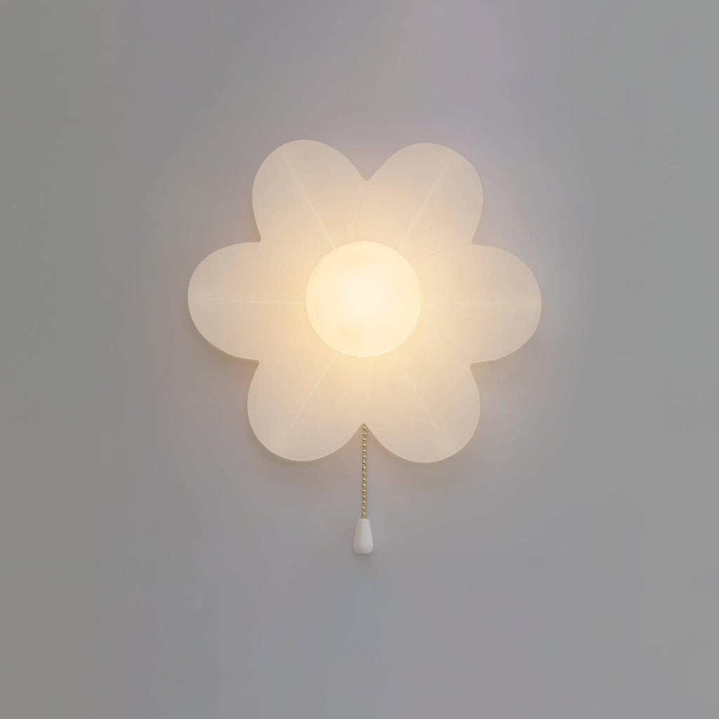 Glowing flower-shaped Clérachic wall light on a grey wall, its petals softly translucent and a white pull at the end of the chain.