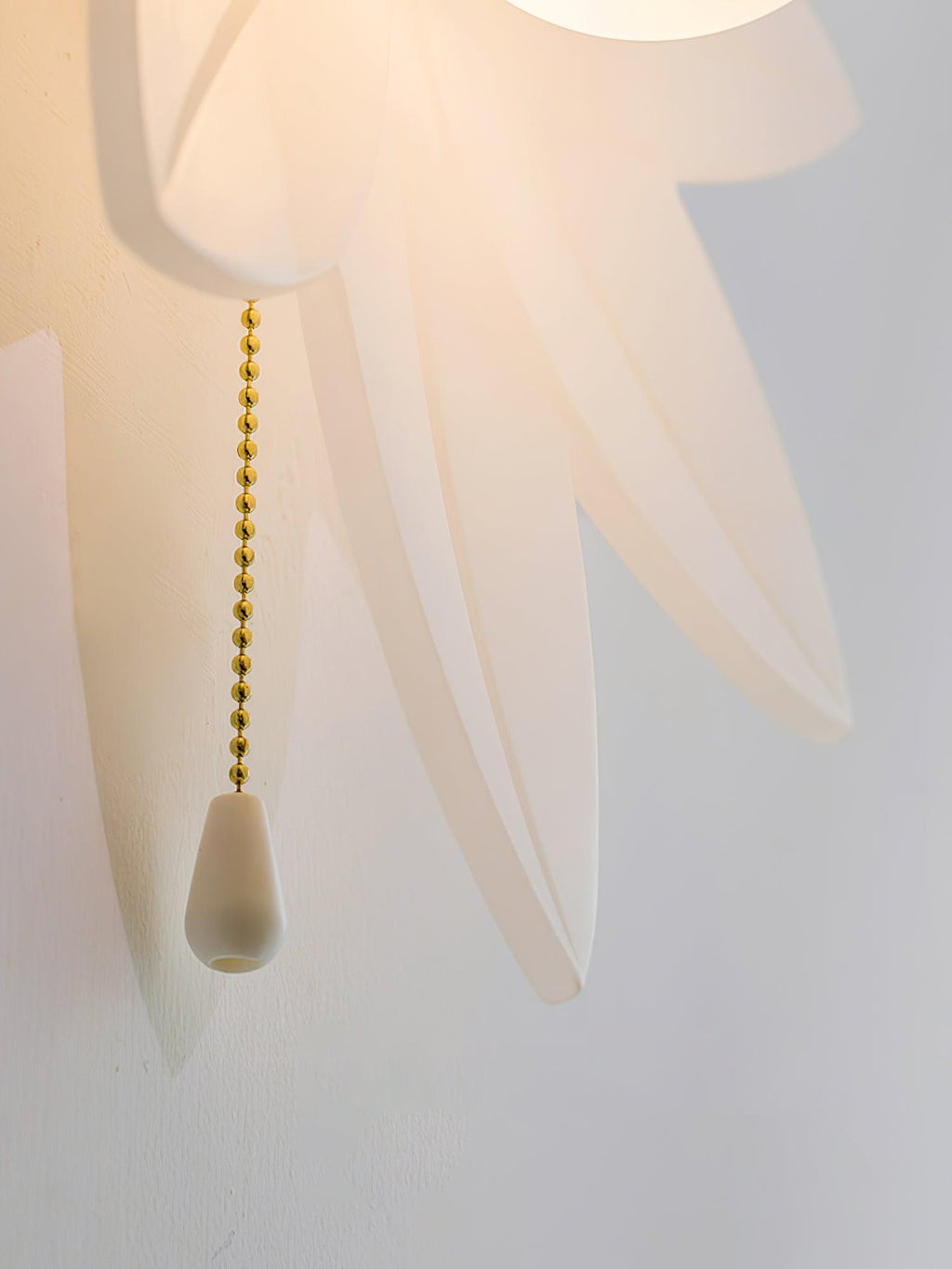 Detail of the translucent petal tips and the gold bead chain with a white pull on this Clérachic flower wall light.