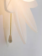 Detail of the translucent petal tips and the gold bead chain with a white pull on this Clérachic flower wall light.