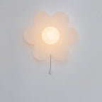 Frosted-white Clérachic flower sconce lit warmly on a pale wall, with a dainty gold chain ending in a white pull.