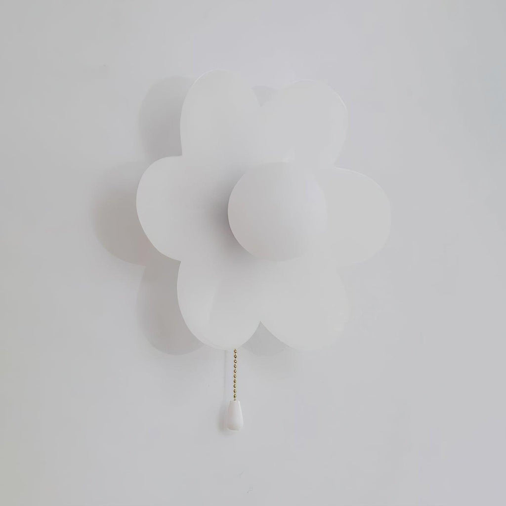 Unlit white Clérachic flower wall light on a pale grey wall, with a flat round globe at the centre and a white chain pull.
