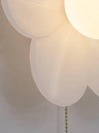 Close view of the folded translucent petals and the glowing globe of this Clérachic wall light, with a gold chain below.