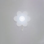 Cool white light from this Clérachic flower wall light on a pale grey wall, the frosted petals and globe glowing bluish-white.