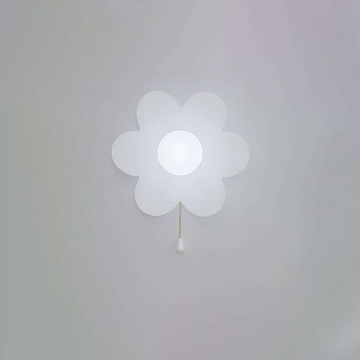 Cool white light from this Clérachic flower wall light on a pale grey wall, the frosted petals and globe glowing bluish-white.