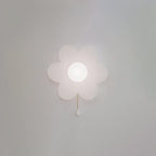 A Clérachic flower wall light with a soft pearly glow on a grey wall, its petals gently translucent and a white pull on the chain.