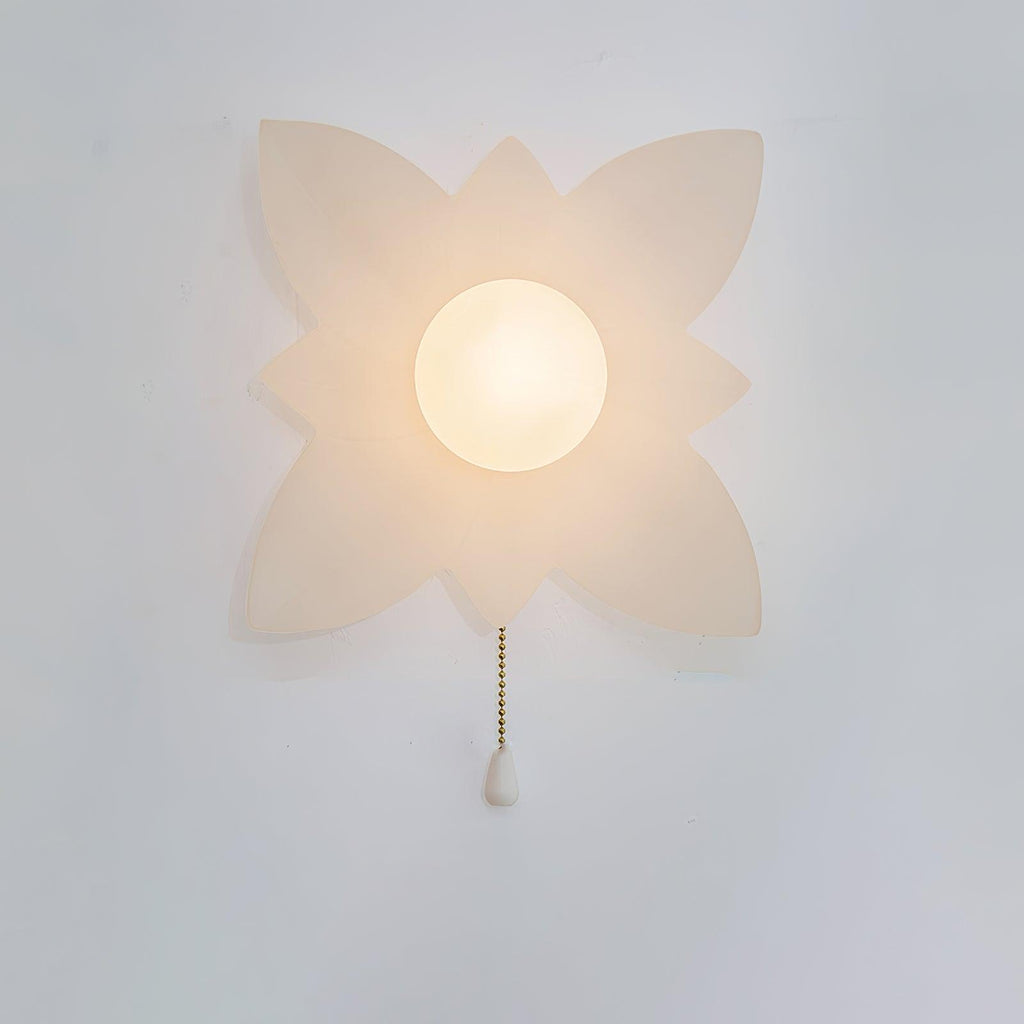 A larger four-point petal wall light from Clérachic with a lit globe and a gold chain, on a pale wall.